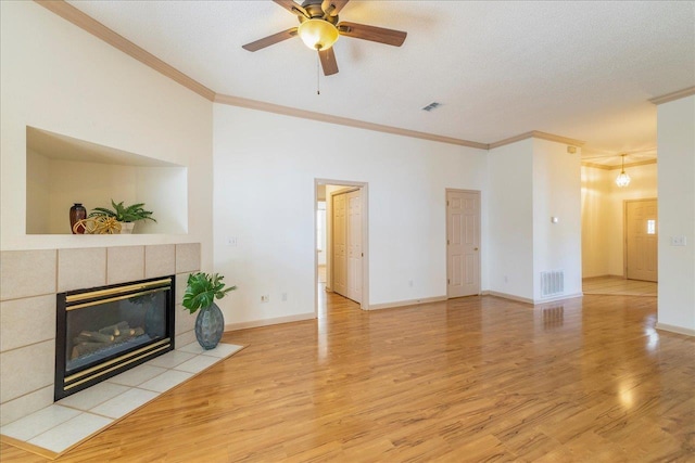 living area with light wood finished floors, a fireplace, visible vents, and ornamental molding