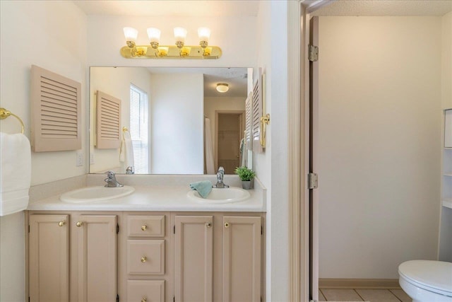 bathroom featuring tile patterned flooring, a sink, toilet, and double vanity