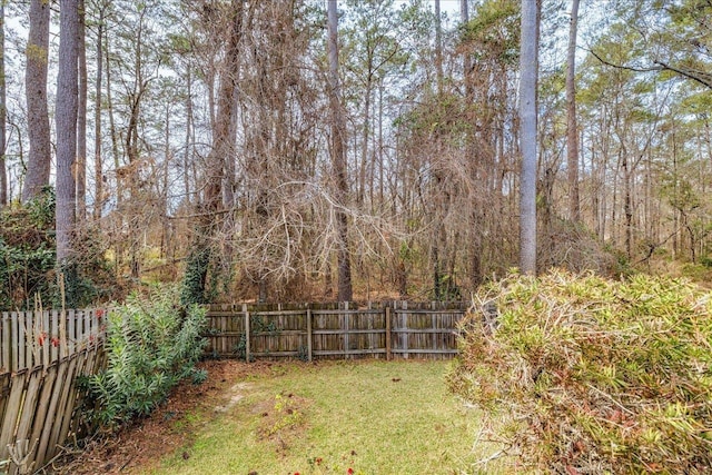 view of yard featuring a forest view and fence