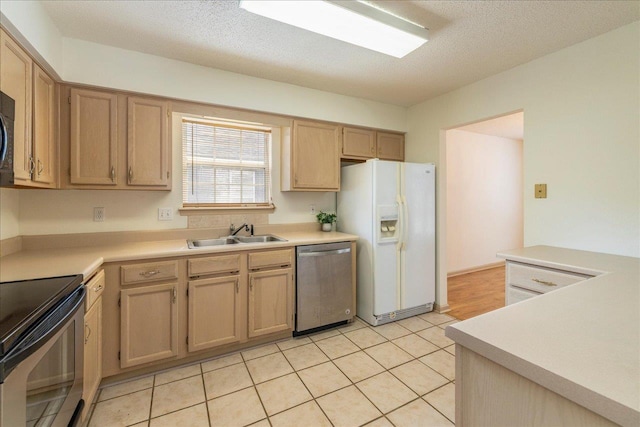 kitchen with stainless steel appliances, light countertops, light tile patterned flooring, a sink, and a textured ceiling