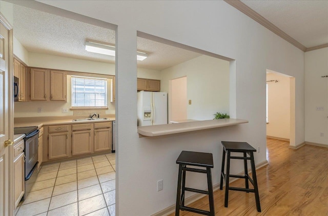 kitchen with a textured ceiling, a breakfast bar, a sink, electric range oven, and white fridge with ice dispenser