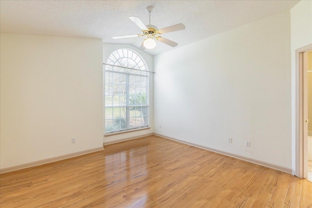 spare room featuring vaulted ceiling, ceiling fan, a textured ceiling, and light wood finished floors