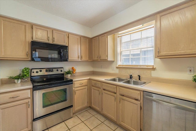 kitchen with appliances with stainless steel finishes, light countertops, a sink, and light brown cabinetry