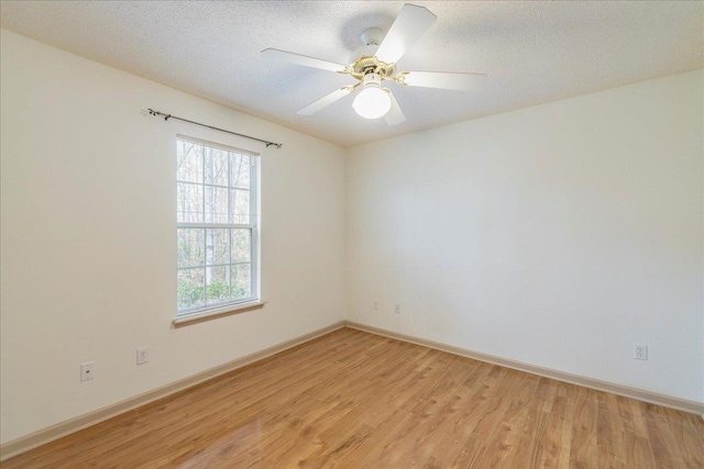 spare room featuring a ceiling fan, baseboards, a textured ceiling, and light wood finished floors