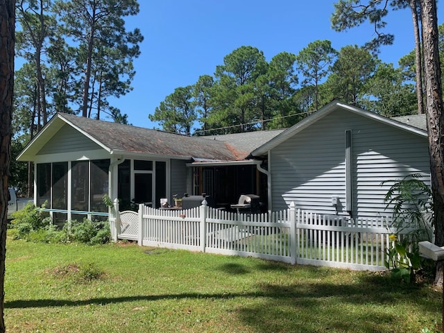 rear view of house featuring a lawn and a sunroom