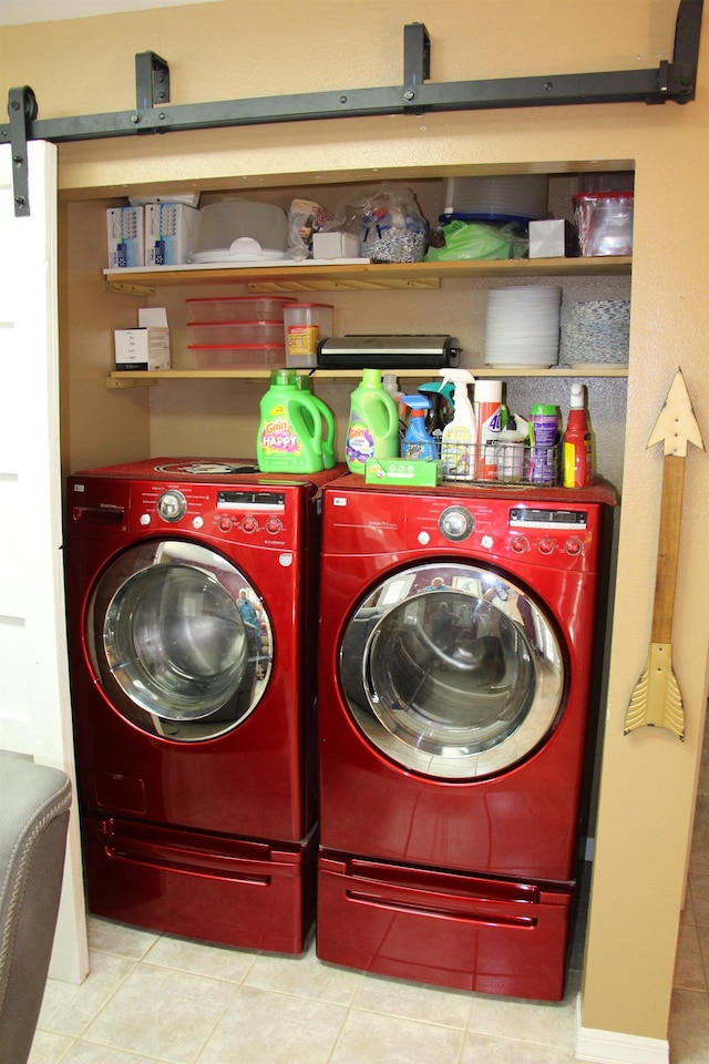 washroom with washer and clothes dryer, a barn door, and light tile patterned floors