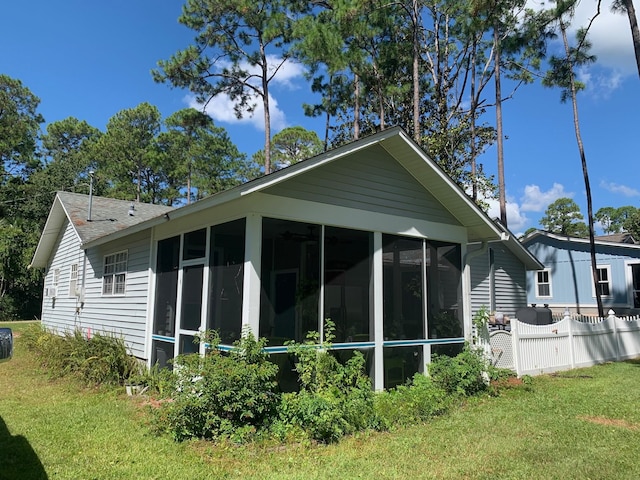 view of property exterior with a sunroom and a lawn