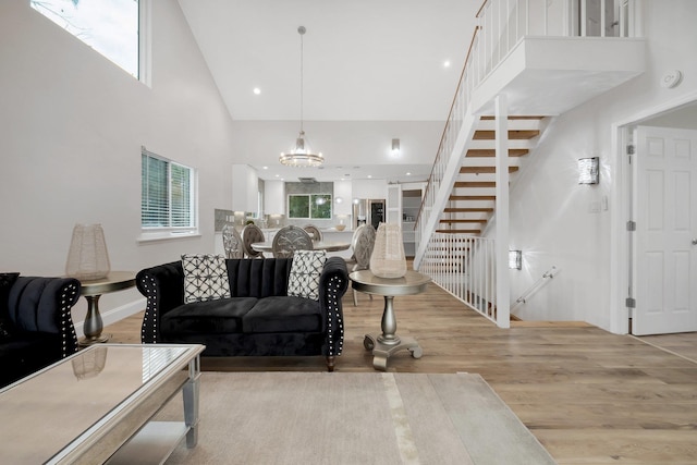 living room with a high ceiling, a chandelier, and light hardwood / wood-style flooring