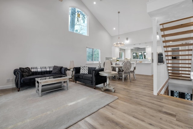 living room with high vaulted ceiling, an inviting chandelier, and light hardwood / wood-style floors