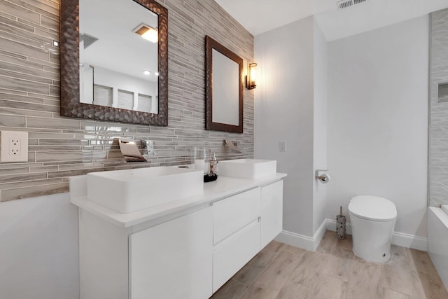 bathroom with vanity, decorative backsplash, wood-type flooring, and toilet