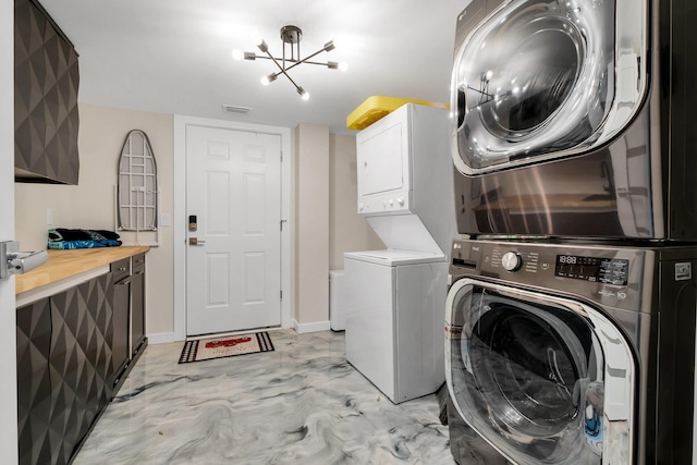 laundry room with stacked washer and clothes dryer and a notable chandelier