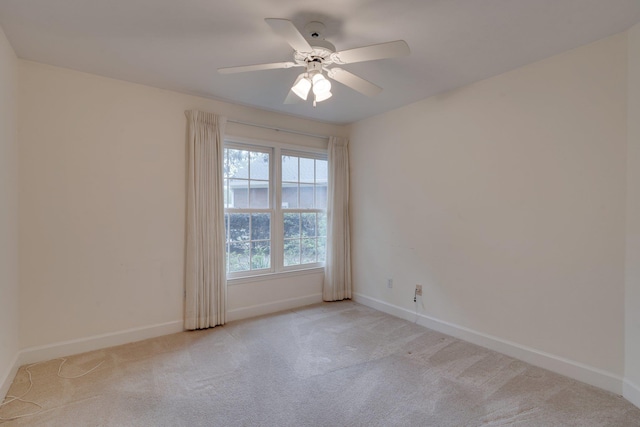 carpeted spare room featuring baseboards and a ceiling fan