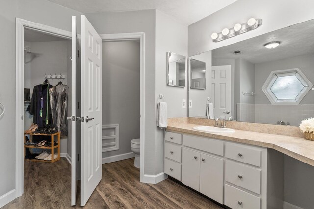 4601 Killimore Ln, Tallahassee, FL 32309 - full bath featuring toilet, vanity, a walk in closet, wood finished floors, and baseboards