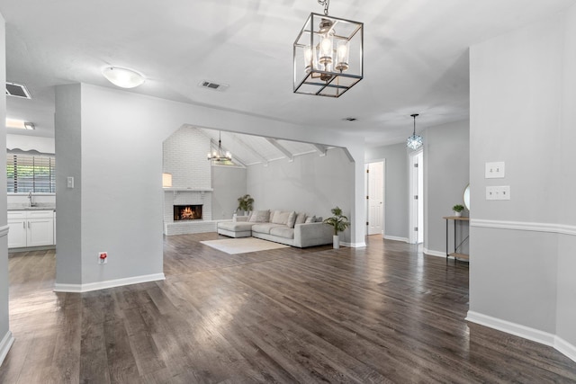 4601 Killimore Ln, Tallahassee, FL 32309 - living room featuring a chandelier, a brick fireplace, dark wood-type flooring, and baseboards