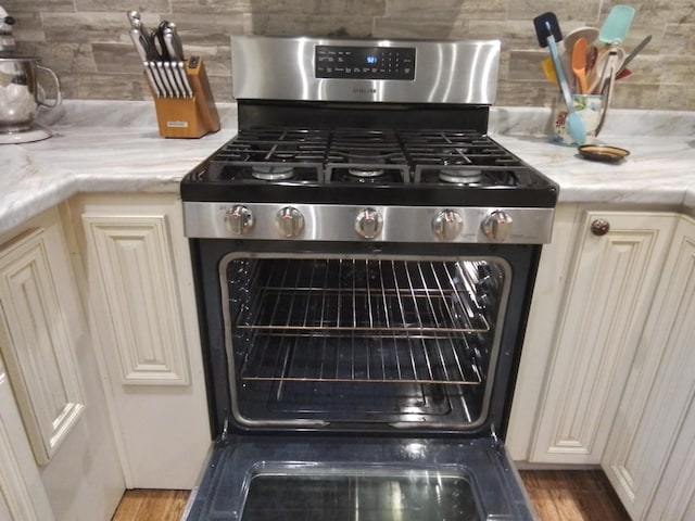 88 Wildwood Dr, Crawfordville, FL 32327 - kitchen view of stainless steel range with gas cooktop, decorative backsplash, and wood finished floors