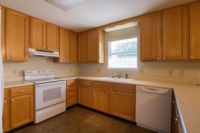 kitchen featuring white appliances, sink, and dark tile patterned floors