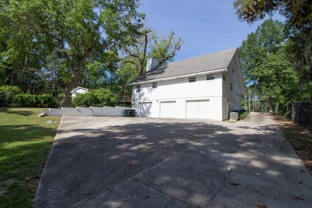 view of property exterior with a garage, central air condition unit, and a yard