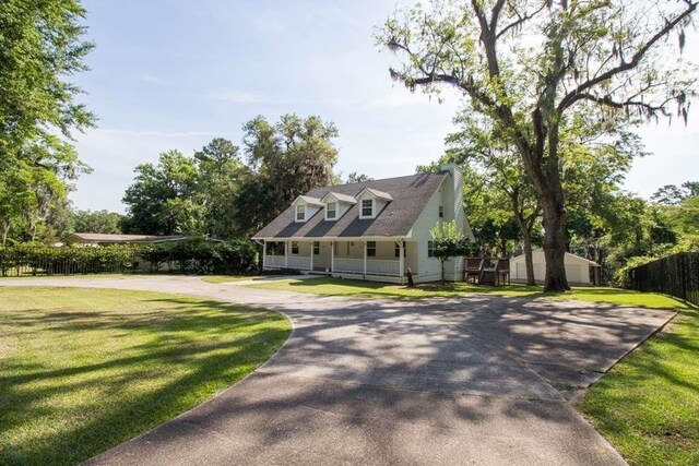 cape cod home with a front yard and covered porch