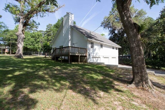 view of side of home with a deck, a garage, and a yard