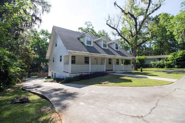 new england style home featuring a porch and a front yard