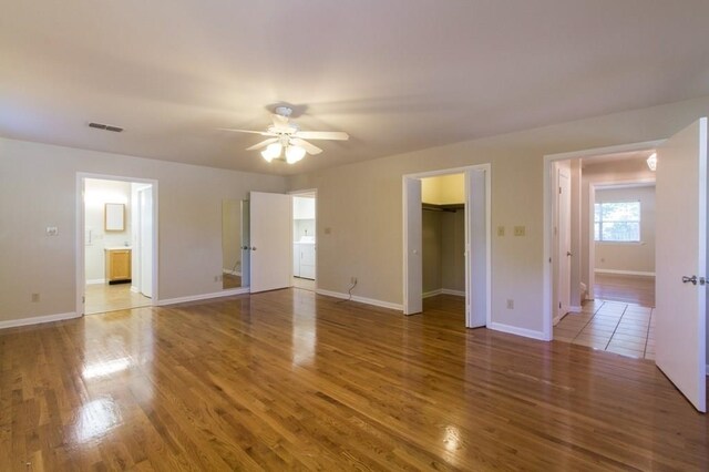 interior space with a spacious closet, hardwood / wood-style flooring, ceiling fan, and ensuite bath