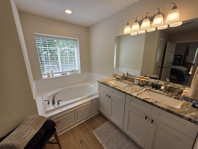 9369 Buck Haven Trl, Tallahassee, FL 32312 - ensuite bathroom with wood finished floors, a bath, double vanity, a textured ceiling, and recessed lighting