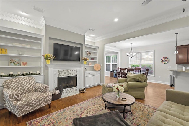2617 Manassas Way, Tallahassee, FL 32312 - living area featuring a tiled fireplace, ornamental molding, light wood-type flooring, a chandelier, and built in features