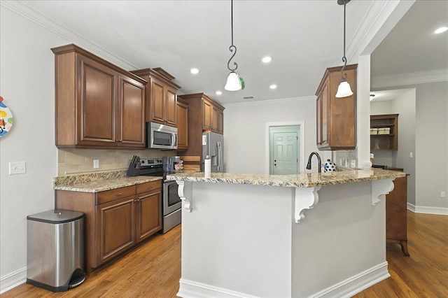 2617 Manassas Way, Tallahassee, FL 32312 - kitchen with appliances with stainless steel finishes, ornamental molding, a kitchen breakfast bar, a peninsula, and light wood-style floors
