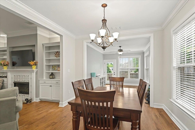 2617 Manassas Way, Tallahassee, FL 32312 - dining room with a chandelier, light wood-type flooring, ceiling fan, a fireplace with raised hearth, and ornamental molding