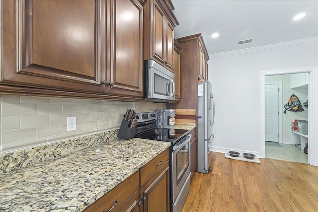 2617 Manassas Way, Tallahassee, FL 32312 - kitchen with stainless steel appliances, tasteful backsplash, light stone countertops, crown molding, and light wood-type flooring