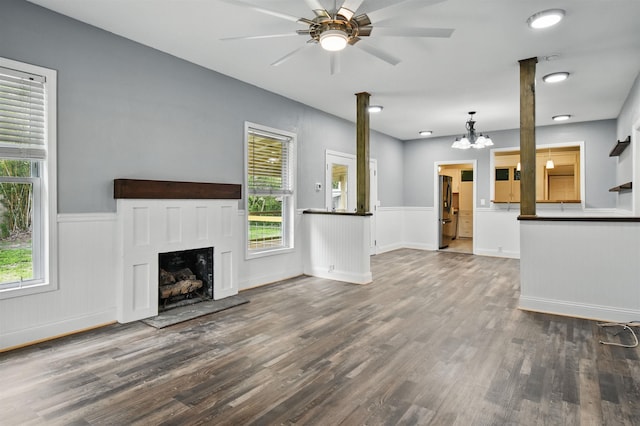 802 N Quincy St, Perry, FL 32347 - unfurnished living room with wood finished floors, ceiling fan, a chandelier, a fireplace with raised hearth, and wainscoting