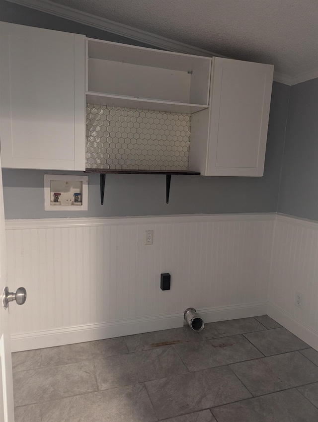 clothes washing area featuring cabinets, washer hookup, a textured ceiling, crown molding, and wooden walls