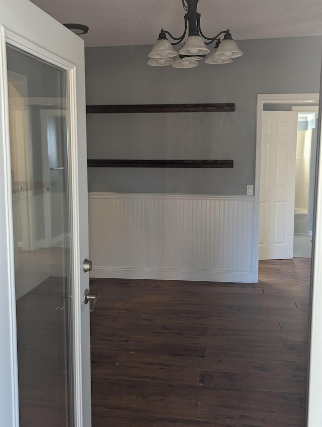 unfurnished dining area featuring dark wood-type flooring and a notable chandelier