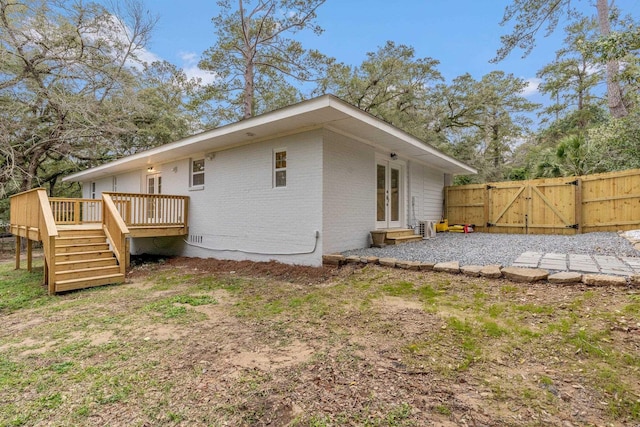 rear view of house with entry steps, a gate, fence, a wooden deck, and brick siding