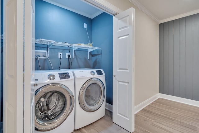 clothes washing area with wood finished floors, separate washer and dryer, crown molding, baseboards, and laundry area