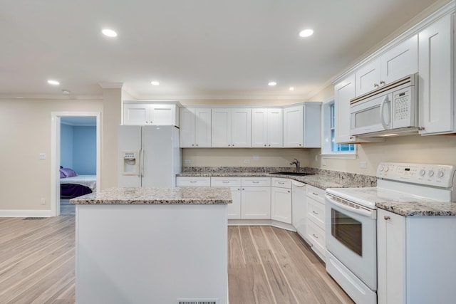 kitchen featuring light wood-style flooring, a sink, a center island, white appliances, and white cabinets