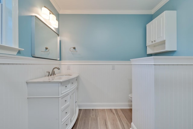 bathroom with crown molding, a wainscoted wall, toilet, wood finished floors, and vanity