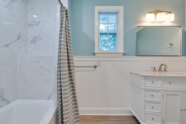 full bathroom with a wainscoted wall, shower / tub combo, wood finished floors, and vanity