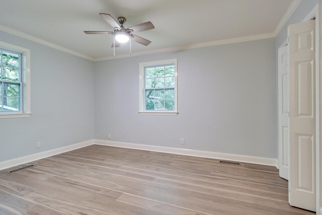 empty room featuring crown molding, visible vents, and light wood-type flooring