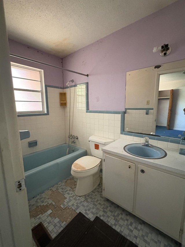 617 Howard Ave, Tallahassee, FL 32310 - bathroom with a textured ceiling, vanity, toilet, tile walls, and shower / bathing tub combination