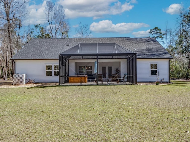 rear view of property with a hot tub, a patio, glass enclosure, and a yard