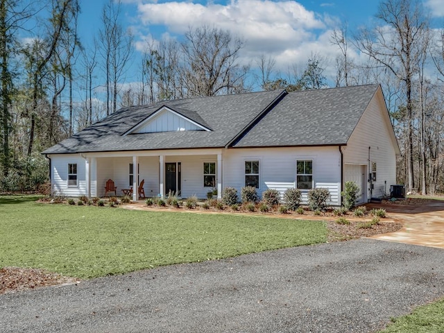 view of front of property with a garage, a porch, central air condition unit, and a front yard