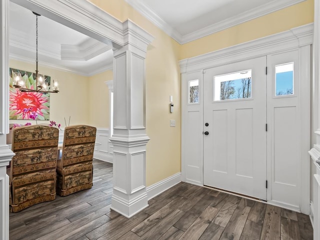 entrance foyer with decorative columns, dark wood-type flooring, crown molding, and an inviting chandelier