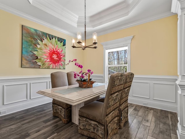 dining space featuring a raised ceiling, crown molding, dark wood-type flooring, and a notable chandelier