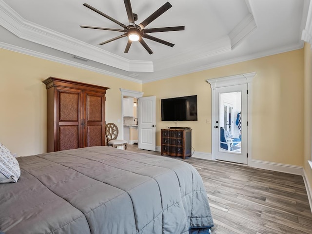 bedroom featuring access to outside, a tray ceiling, ceiling fan, wood-type flooring, and crown molding