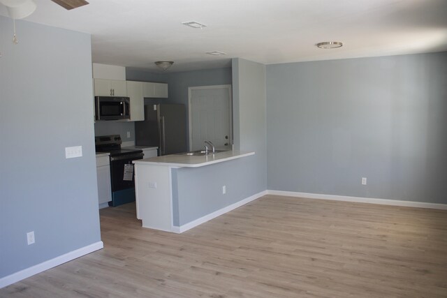 kitchen with black appliances, white cabinetry, kitchen peninsula, and light hardwood / wood-style floors