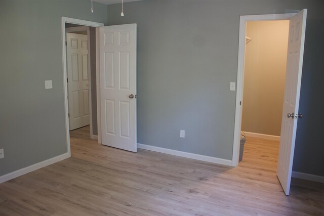 unfurnished bedroom featuring light wood-type flooring and a spacious closet