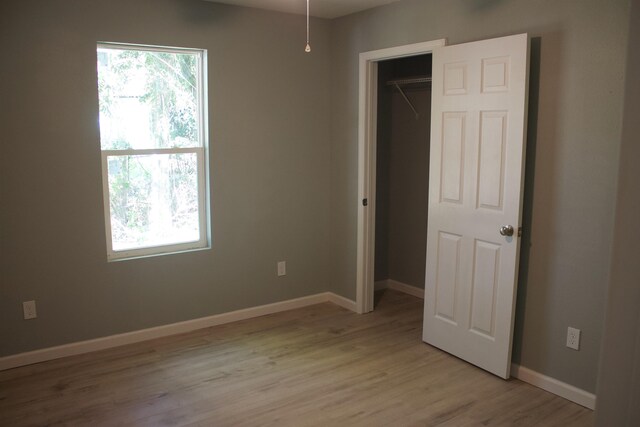 unfurnished bedroom featuring a closet, a walk in closet, and light hardwood / wood-style floors