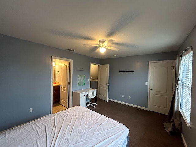 bedroom with connected bathroom, dark carpet, and ceiling fan