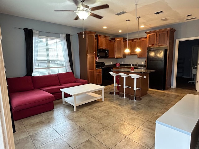 kitchen with a kitchen breakfast bar, ceiling fan, black appliances, pendant lighting, and a kitchen island